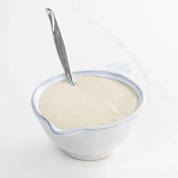 tahini dressing in a small pitcher with a spoon