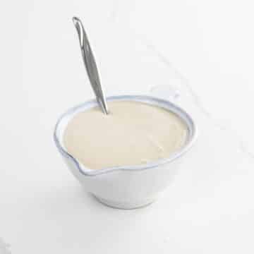 tahini dressing in a small pitcher with a spoon