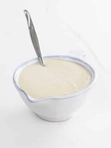 tahini dressing in a small pitcher with a spoon