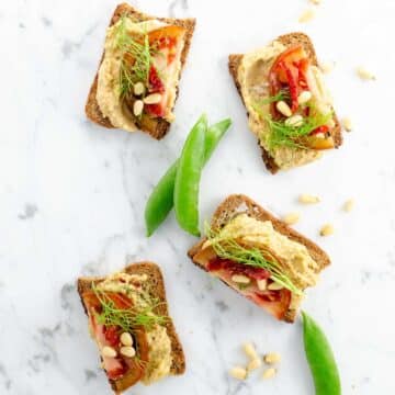 white bean crostini and snap peas on a marble background