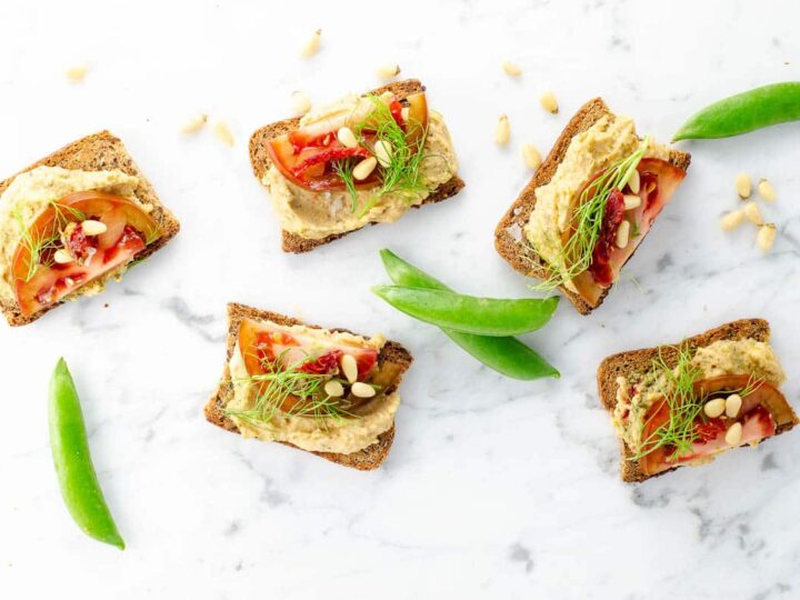 white bean crostini and snap peas on a marble background