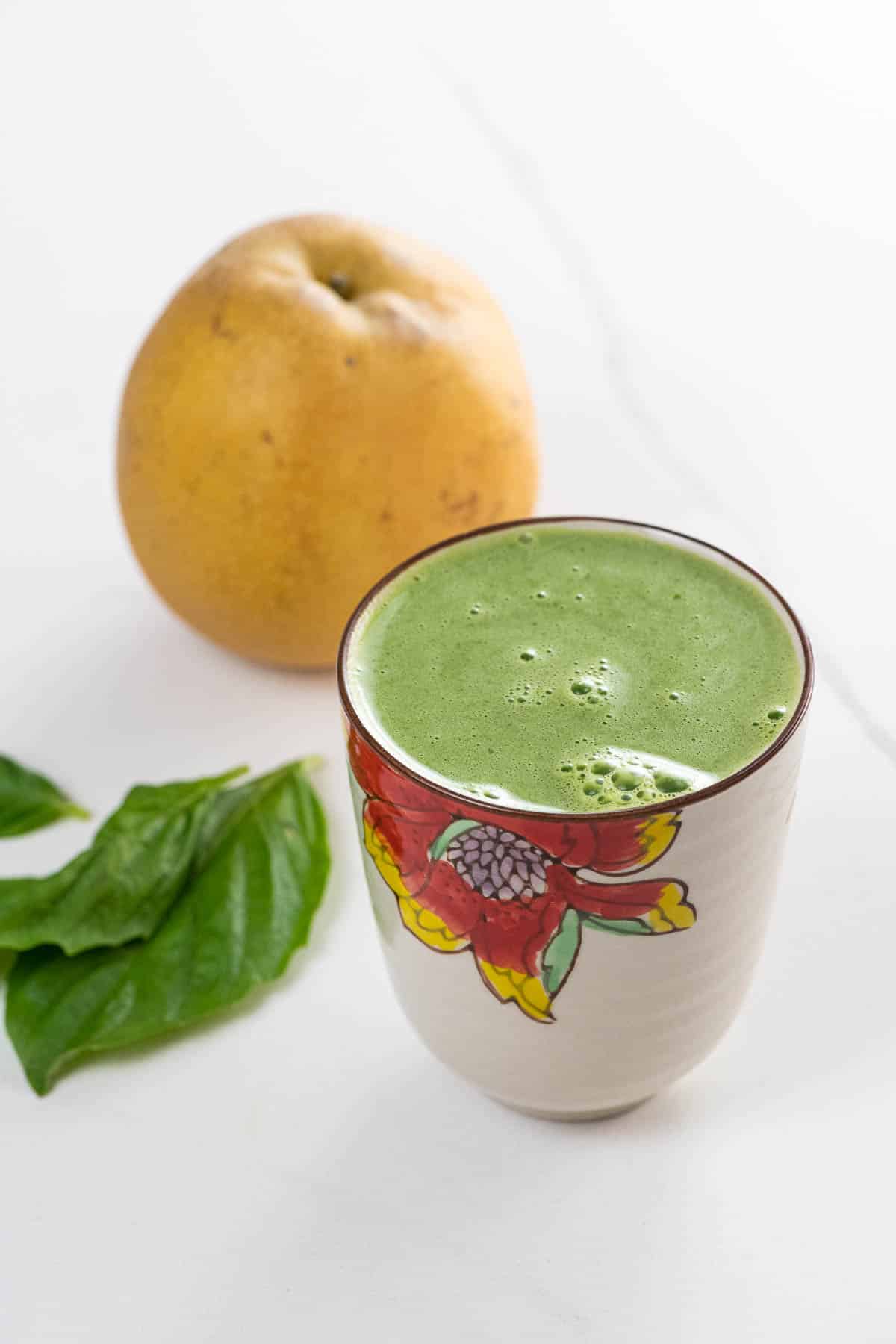 asian pear juice with basil, lemon, and celery in a decorative glass with basil leaves and an asian pear