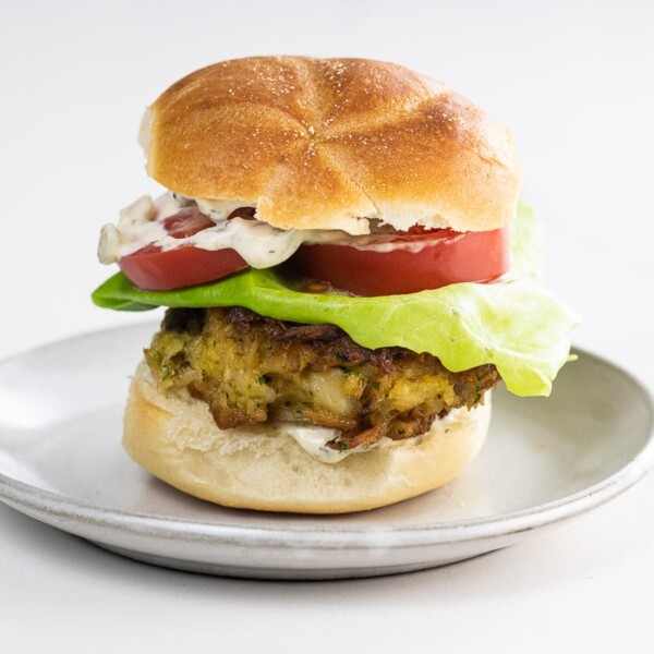 a crab cake sandwich on a kaiser roll with lettuce, tomato, and tartar sauce
