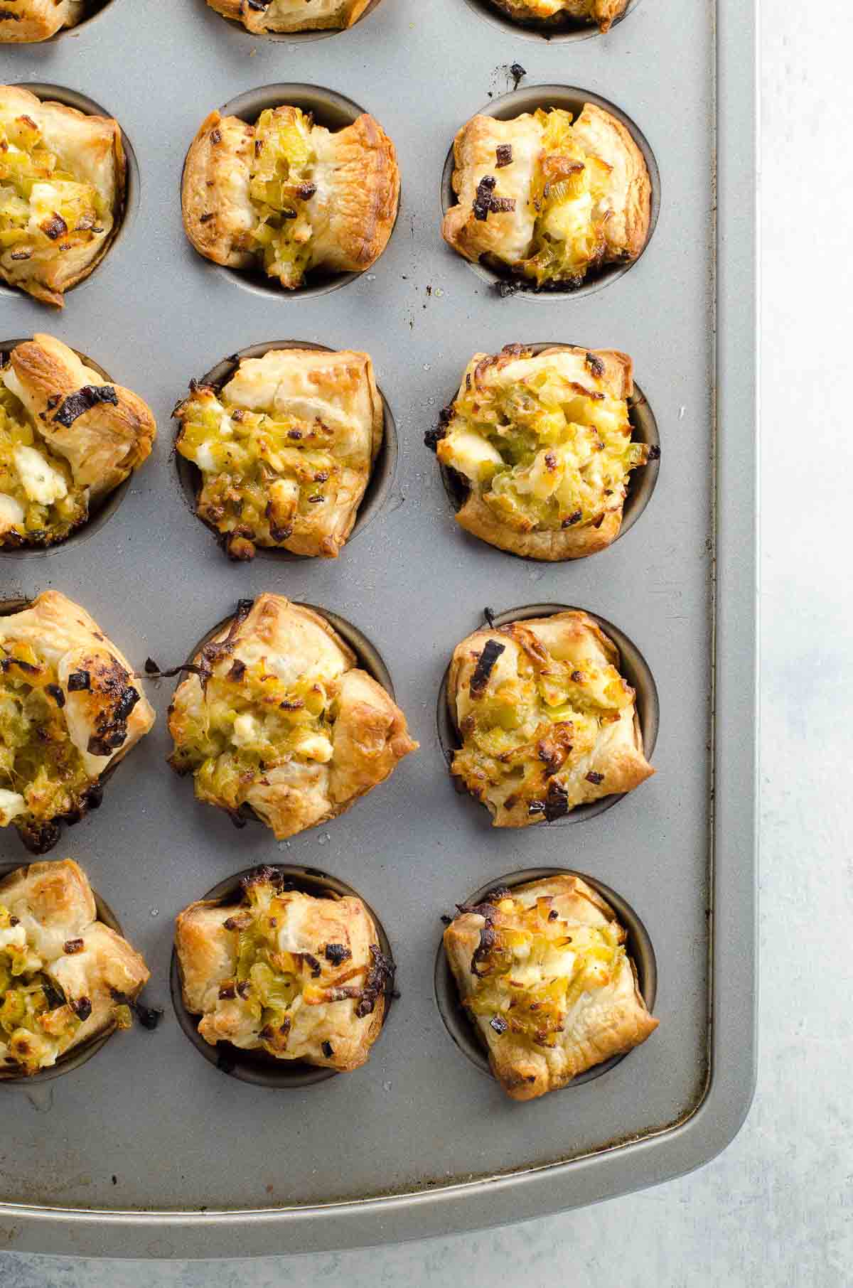 leek and feta puff pastry cup appetizers in a mini muffin tin