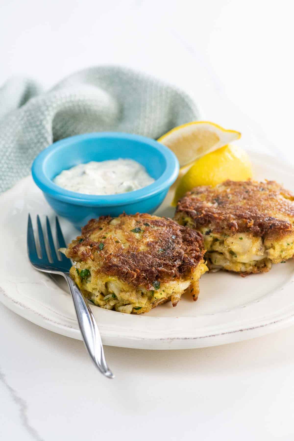old bay crab cakes on a plate with tartar sauce and lemon