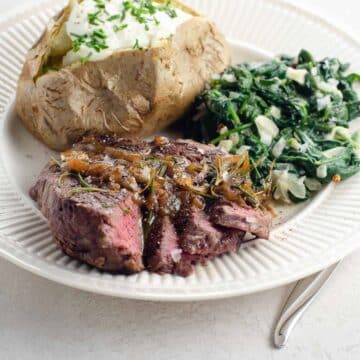pan seared filet mignon with an easy pan sauce, on a plate with spinach and a baked potato