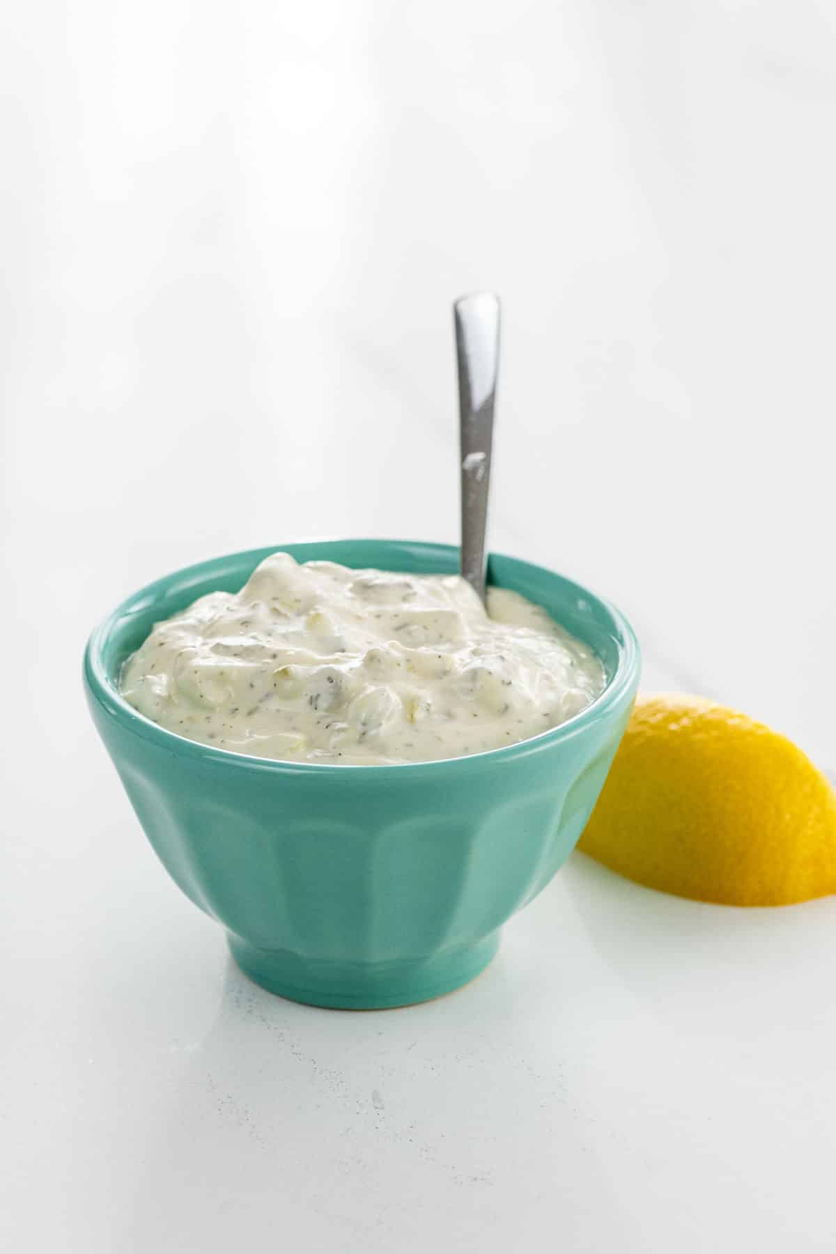 tartar sauce for crab cakes, fish, oysters, and more in a small bowl with a spoon and a lemon wedge