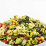 black bean corn avocado salad with jicama in a white bowl with a wooden spoon