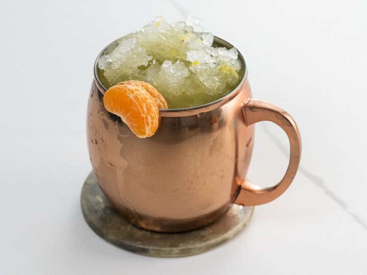 an orange moscow mule in a copper mug garnished with clementine segments