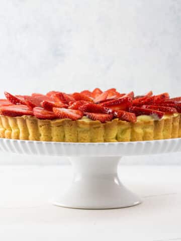a strawberry custard tart on a cake stand