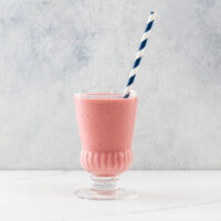 a strawberry lemonade smoothie in a glass with a straw