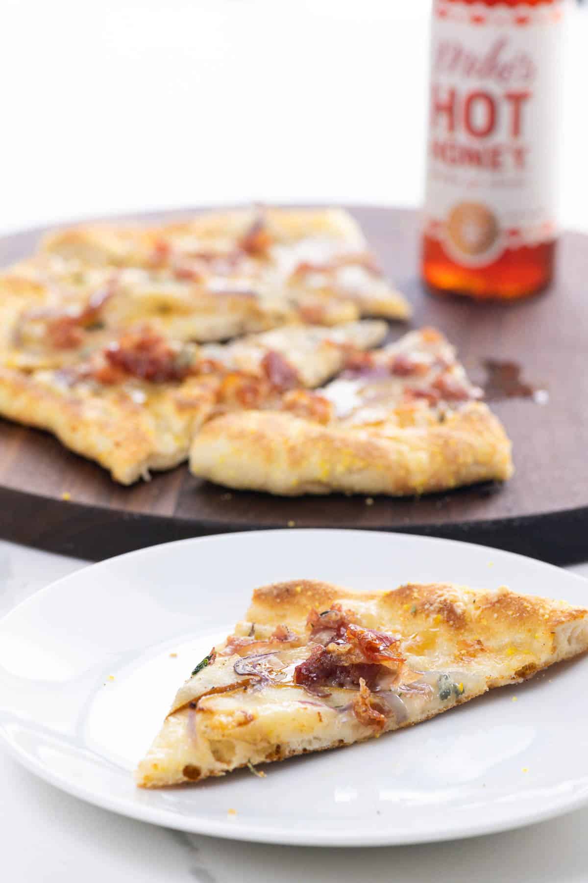 pear gorgonzola pizza with prosciutto and hot honey on a cutting board and a plate