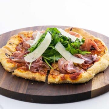 prosciutto and arugula pizza on a cutting board