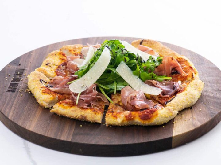 prosciutto and arugula pizza on a cutting board