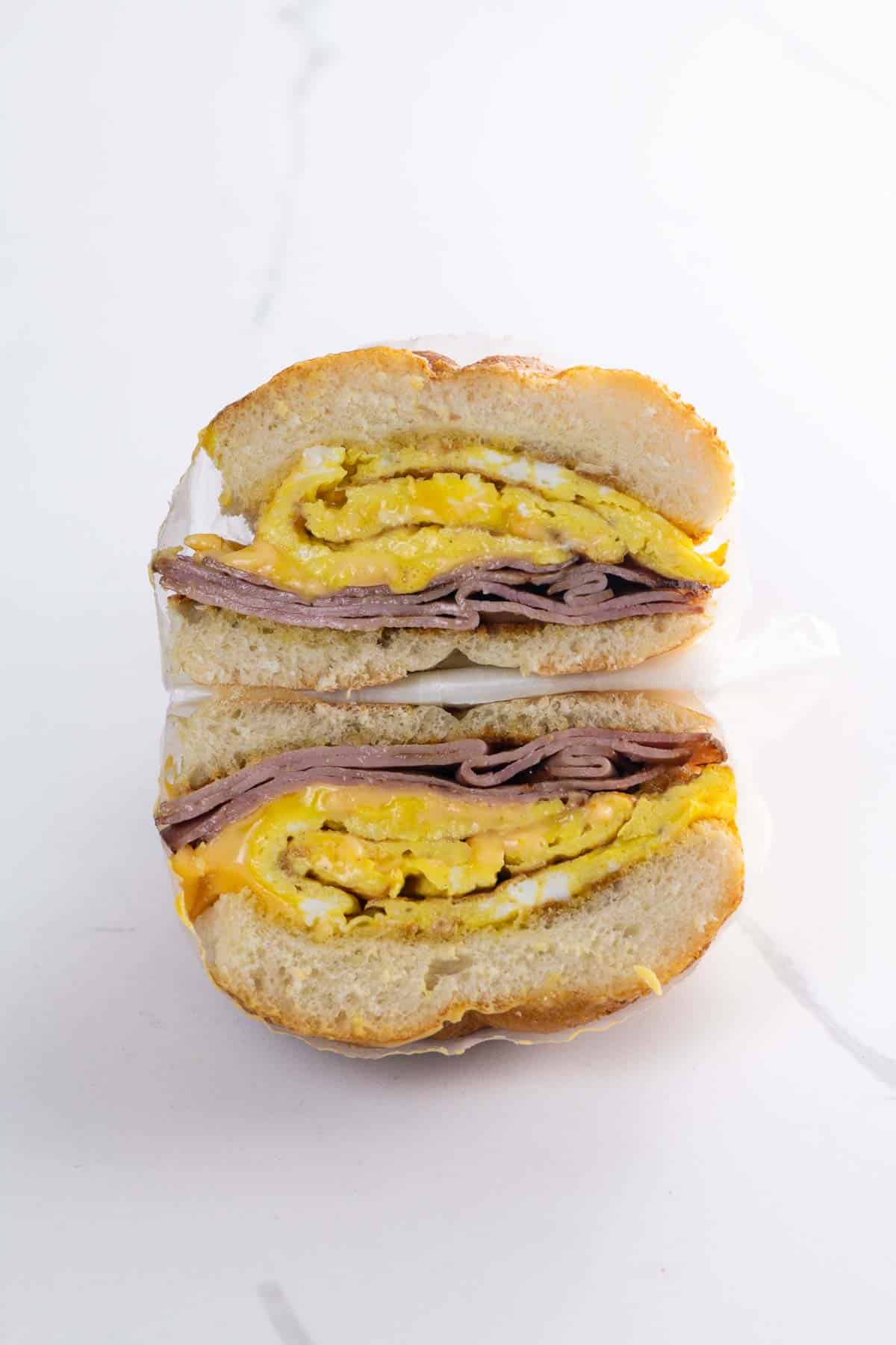 a ham egg and cheese sandwich on a kaiser roll wrapped in deli paper