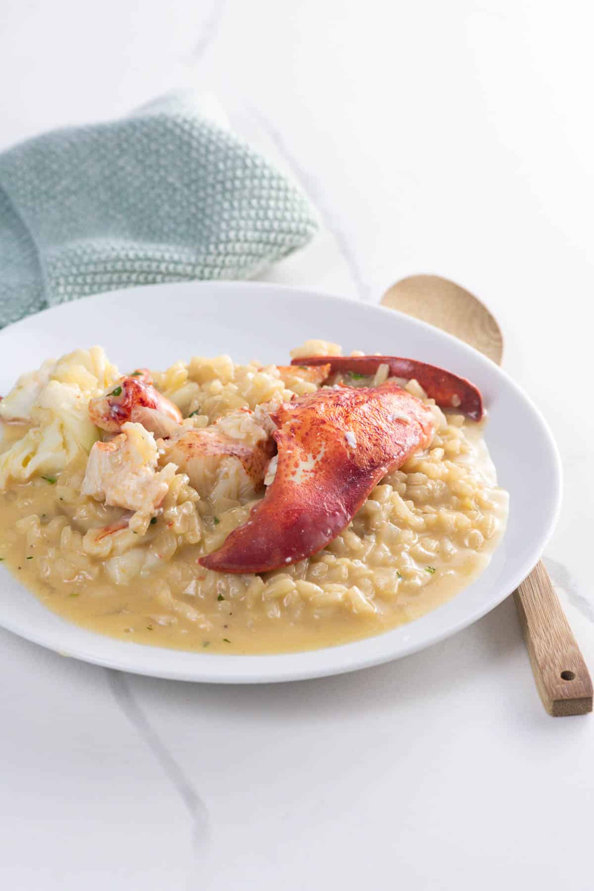 lobster risotto on a plate with a napkin and a small wooden spoon