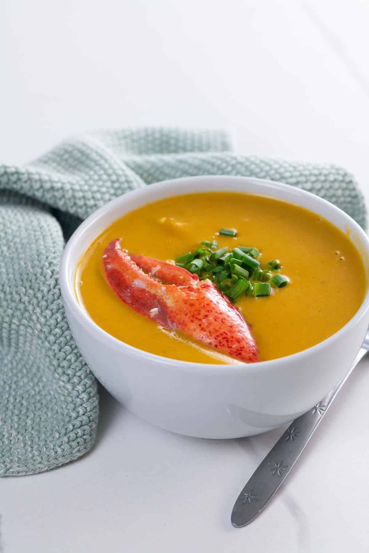 Maine lobster bisque in a bowl with a spoon and a napkin