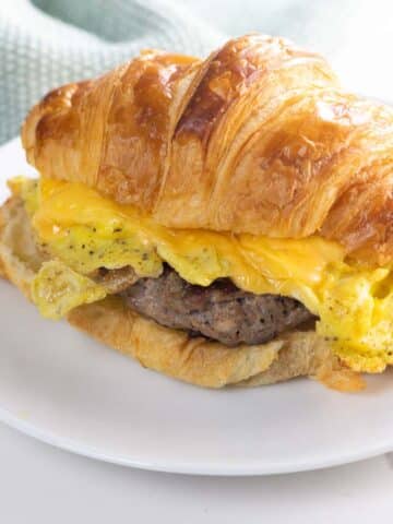 a sausage egg and cheese croissant on a plate with a napkin
