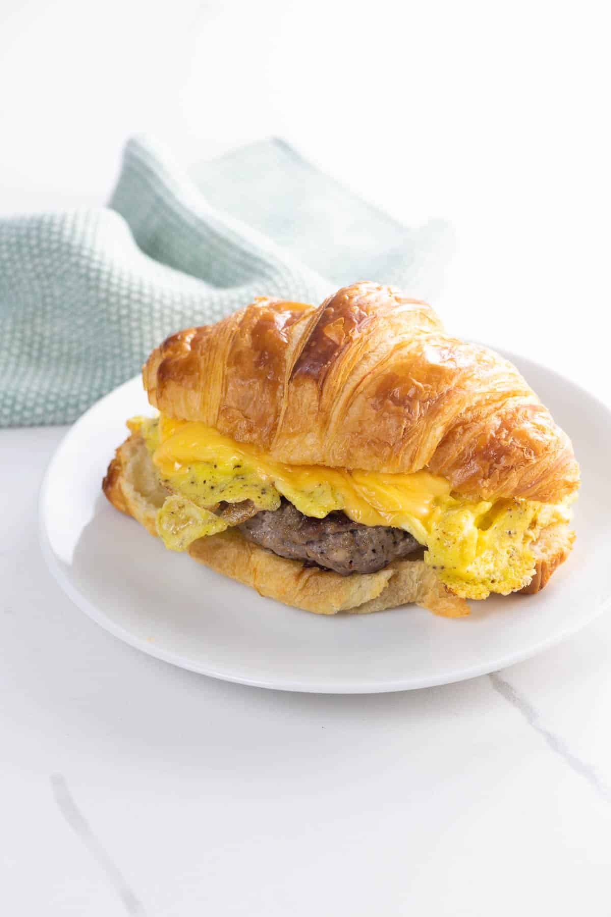 a sausage egg and cheese croissant on a plate with a napkin