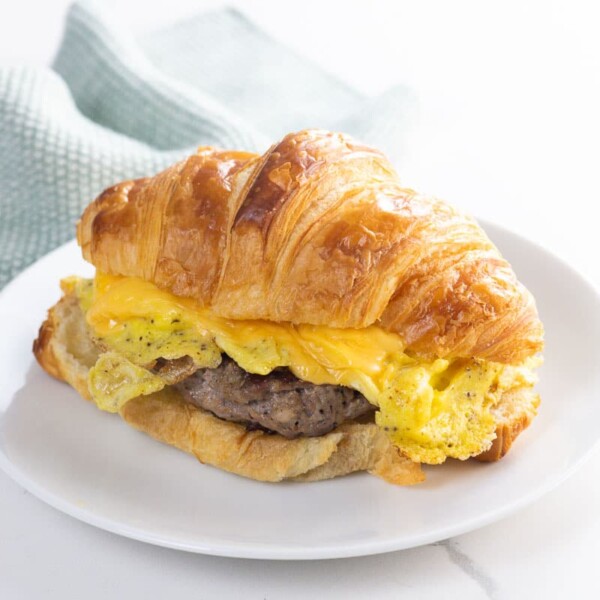 a sausage egg and cheese croissant on a plate with a napkin