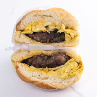 a sausage egg and cheese sandwich on a kaiser roll wrapped in deli paper