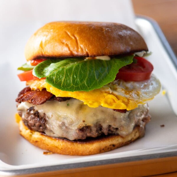 a breakfast burger with cheddar, bacon, and fried egg on a brioche bun