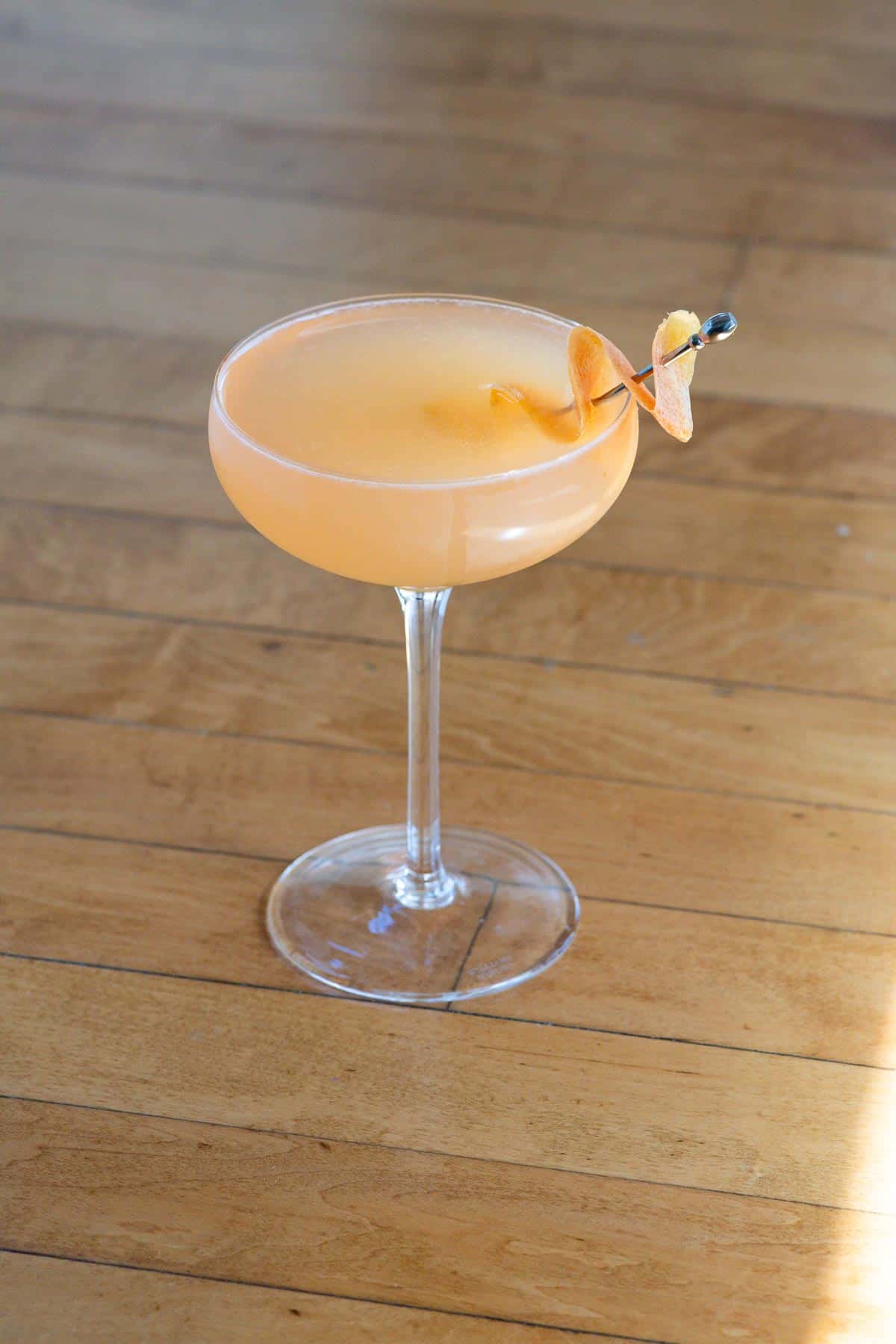a french blonde cocktail in a coupe glass on a table