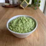 a bowl with garlic scape pesto on a table