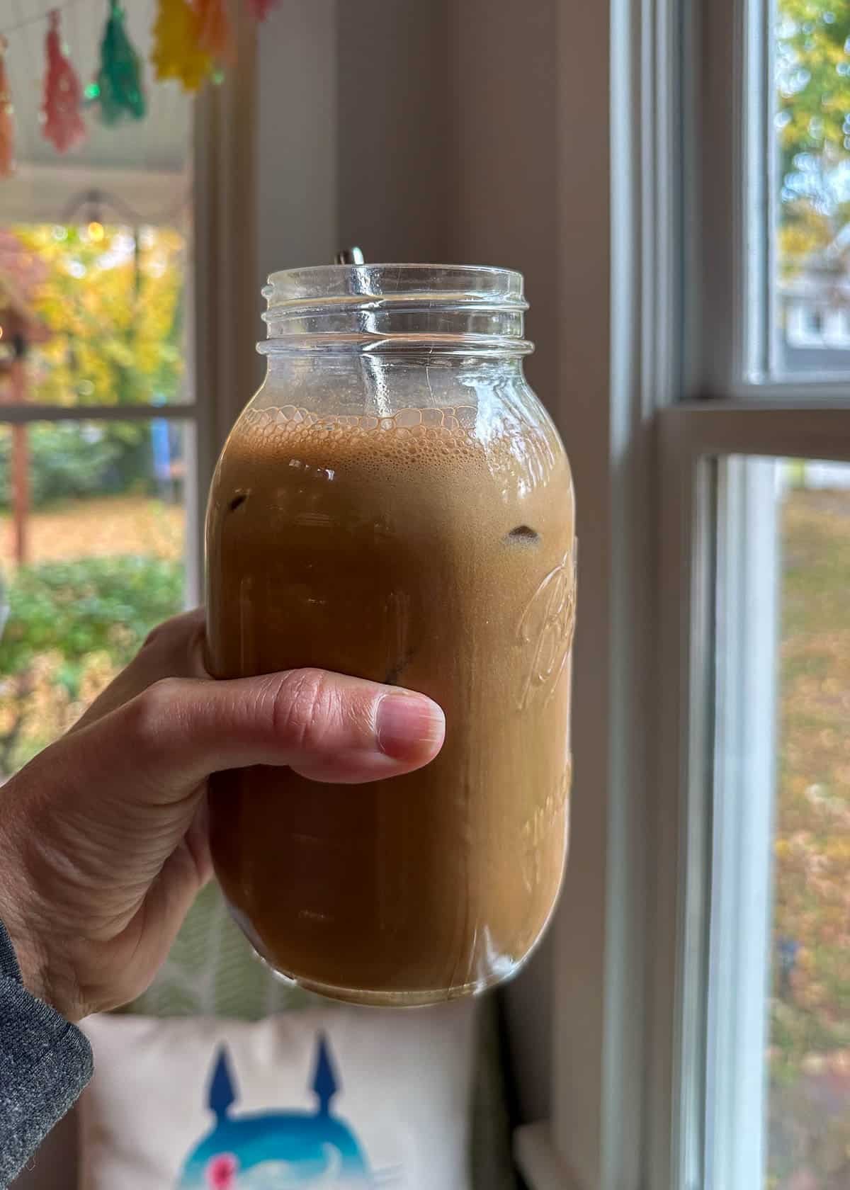 holding a mason jar full of protein coffee