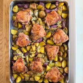 chicken thighs, potatoes, and artichoke hearts in a pan