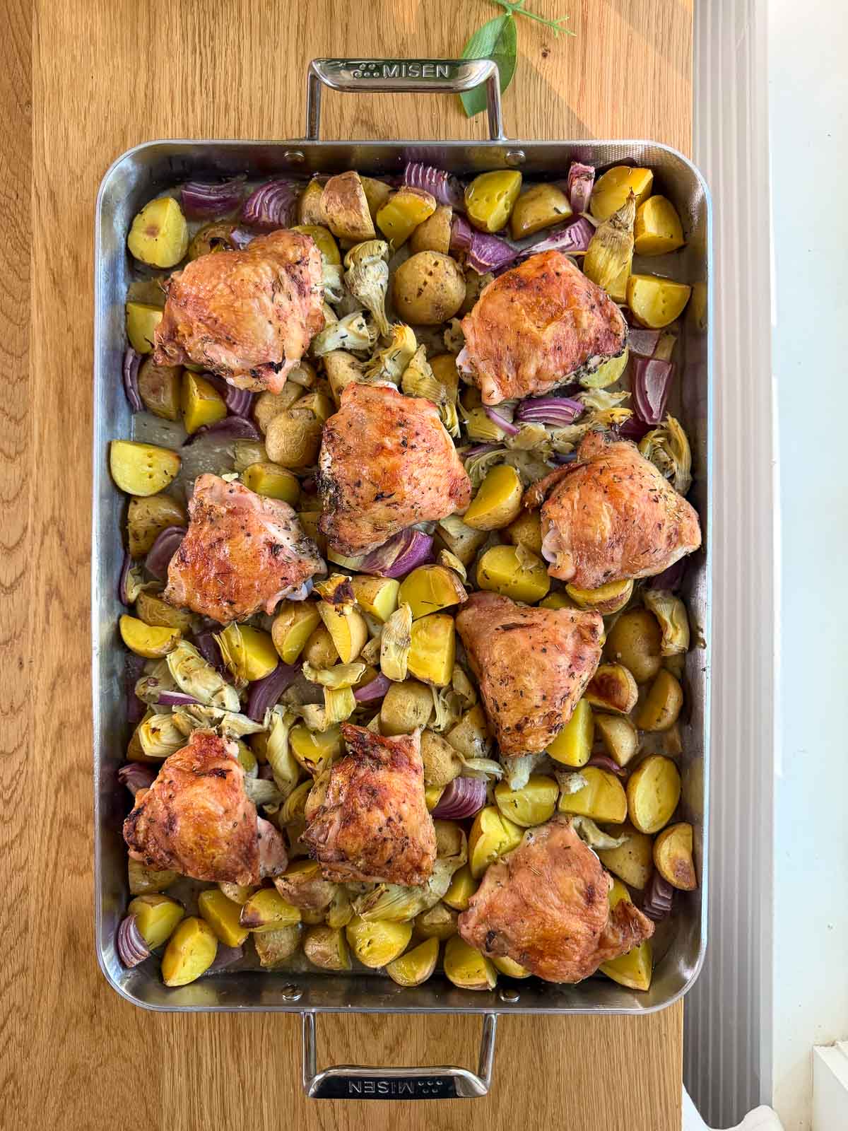 chicken thighs, potatoes, and artichoke hearts in a pan
